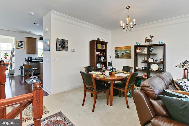 dining area with an inviting chandelier, baseboards, ornamental molding, and light colored carpet