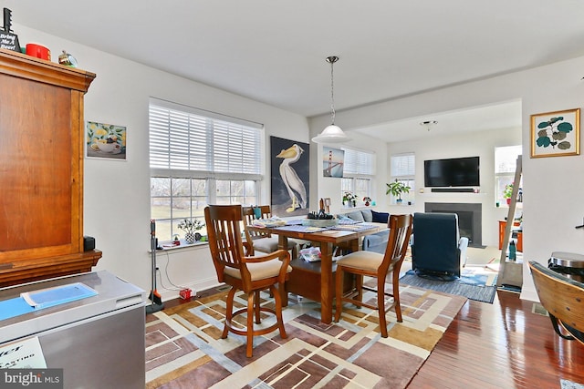 dining room with light wood finished floors, a fireplace, and baseboards