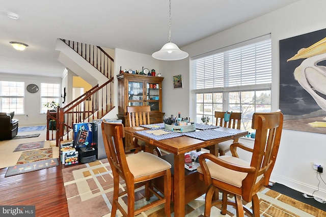 dining room featuring wood finished floors, baseboards, and stairs