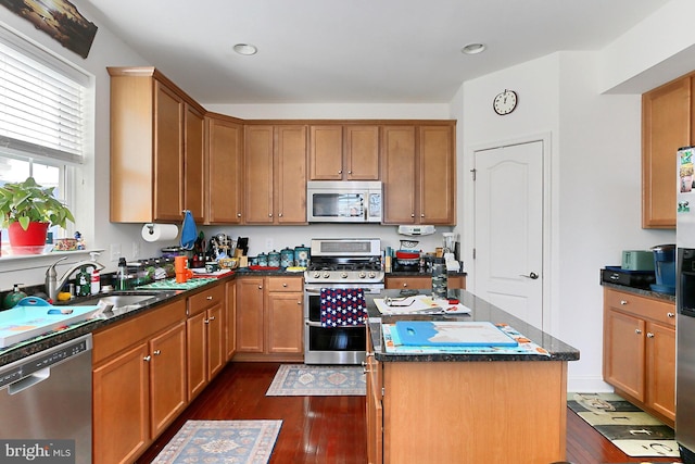 kitchen with dark wood finished floors, a kitchen island, brown cabinets, stainless steel appliances, and a sink