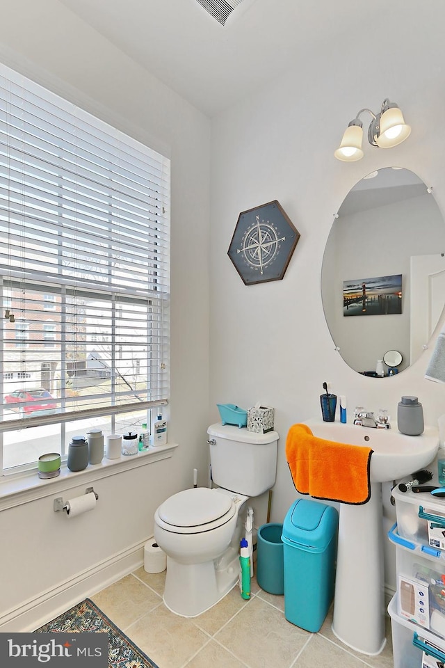 half bath with baseboards, a sink, toilet, and tile patterned floors