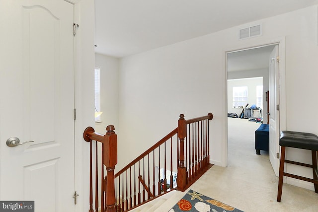 hall featuring visible vents, carpet flooring, an upstairs landing, and baseboards