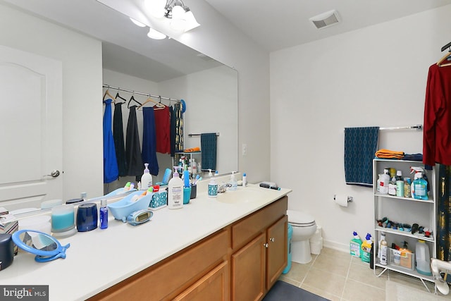 bathroom featuring tile patterned flooring, toilet, vanity, visible vents, and baseboards