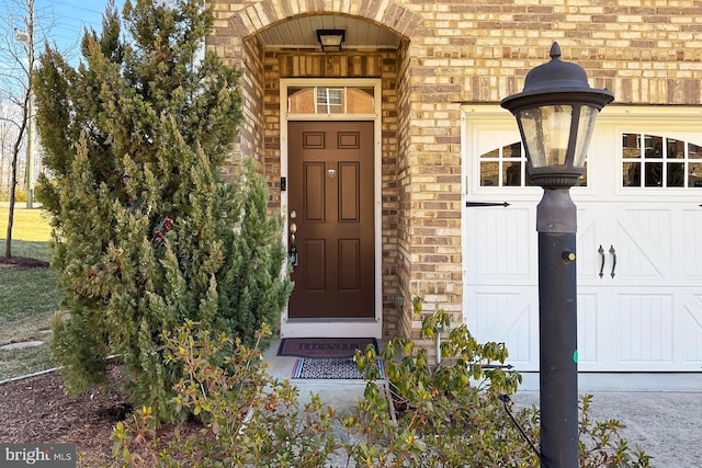 property entrance featuring a garage, stone siding, and brick siding