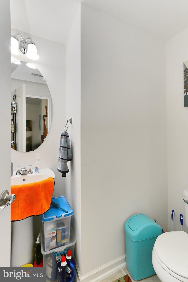 bathroom with toilet, baseboards, visible vents, and a sink