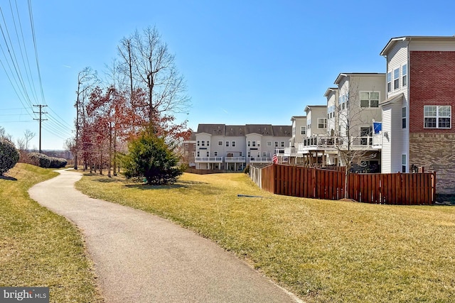 view of community featuring a residential view, fence, and a lawn