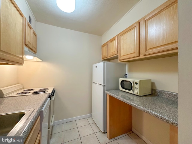 kitchen featuring dark countertops, light brown cabinetry, light tile patterned flooring, white appliances, and under cabinet range hood