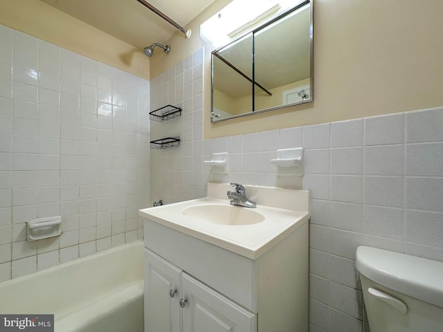 bathroom with toilet, shower / bathing tub combination, tile walls, and vanity