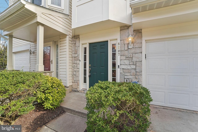 property entrance featuring a garage and stone siding