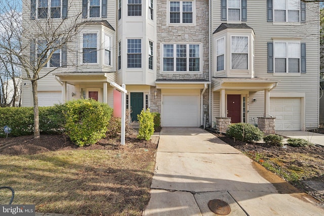 townhome / multi-family property featuring a garage, stone siding, and driveway