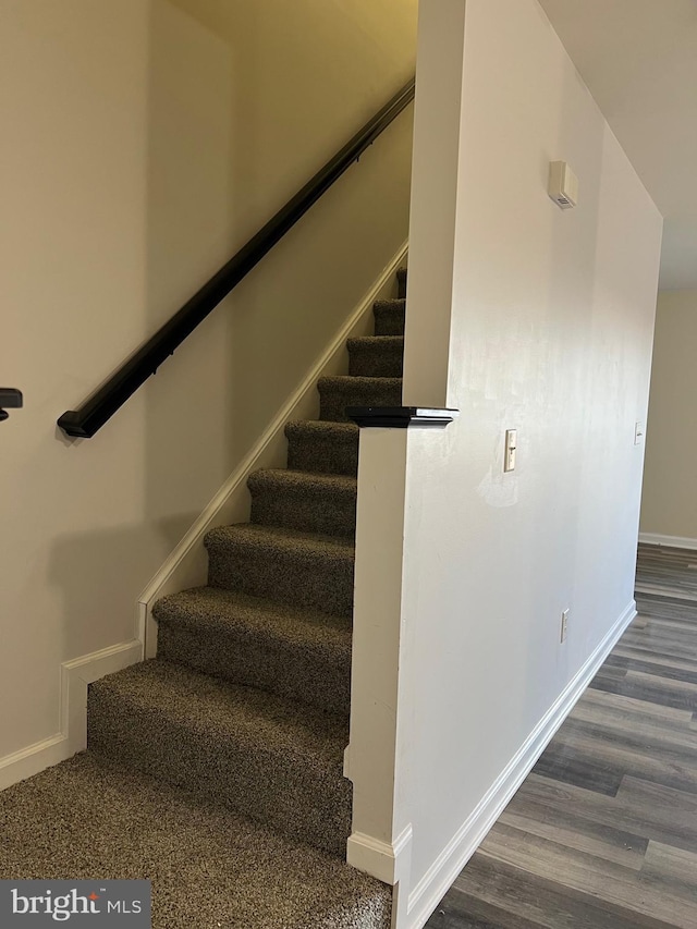 staircase with baseboards and wood finished floors