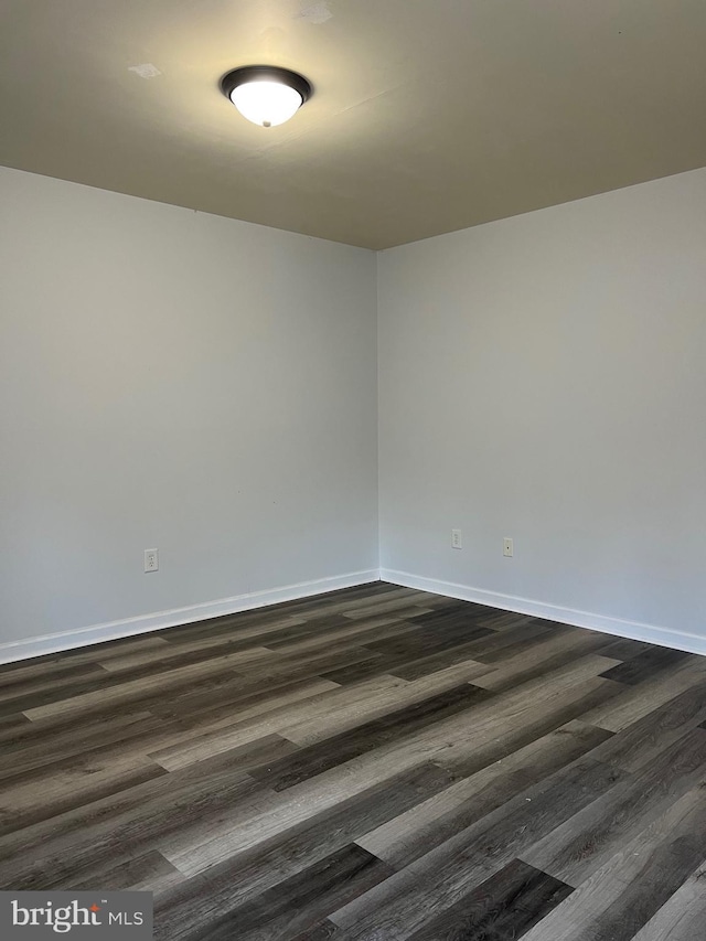 empty room featuring dark wood-style floors and baseboards