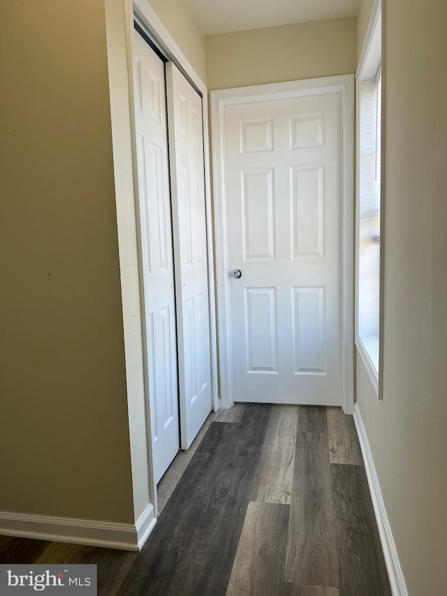 hallway featuring dark wood-style flooring and baseboards