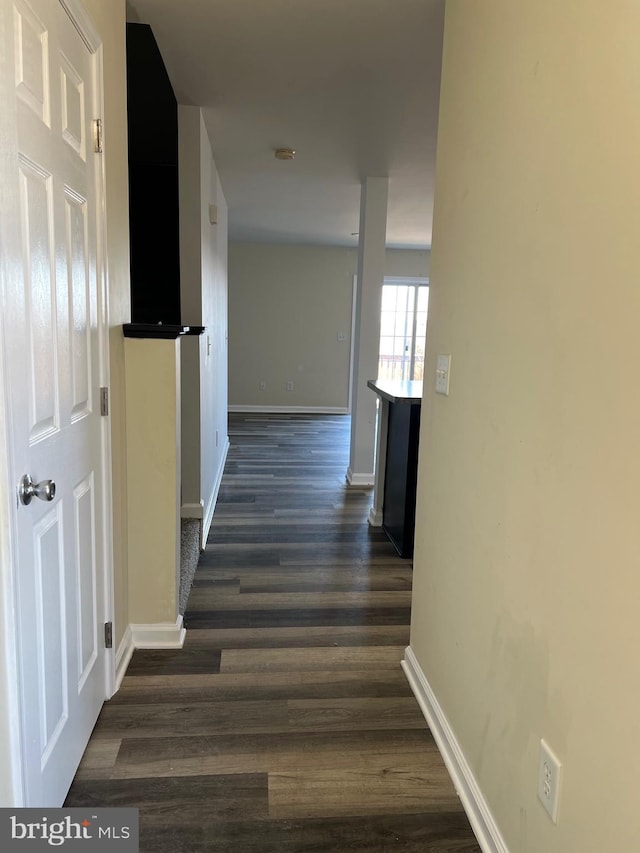 corridor with dark wood finished floors and baseboards