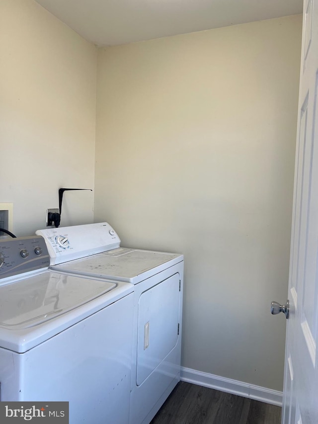 laundry area with dark wood-type flooring, washing machine and dryer, laundry area, and baseboards