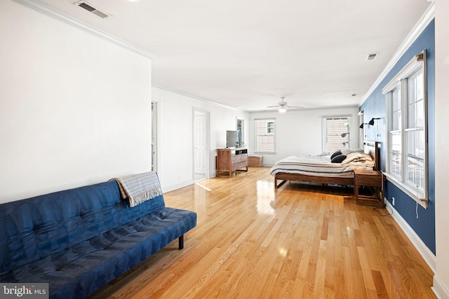 bedroom featuring wood finished floors, baseboards, ornamental molding, and visible vents