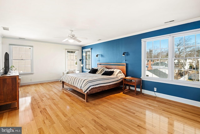 bedroom with crown molding, baseboards, visible vents, and light wood-style flooring