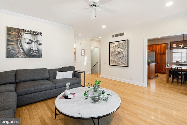 living area with light wood-type flooring, ornamental molding, baseboards, and visible vents