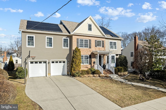 view of front facade featuring brick siding, roof mounted solar panels, concrete driveway, and a garage