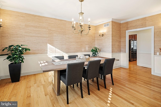 dining space with ornamental molding, light wood-style floors, an inviting chandelier, and visible vents