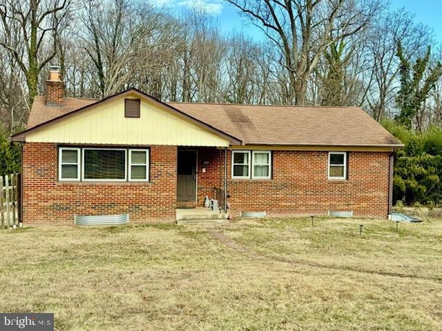 ranch-style home with brick siding, a chimney, and a front lawn