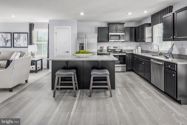 kitchen featuring a breakfast bar area, a sink, open floor plan, appliances with stainless steel finishes, and a center island