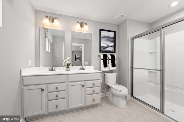 full bath featuring toilet, a sink, visible vents, double vanity, and a stall shower