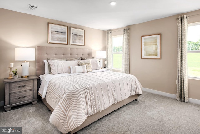 bedroom with baseboards, visible vents, and light colored carpet