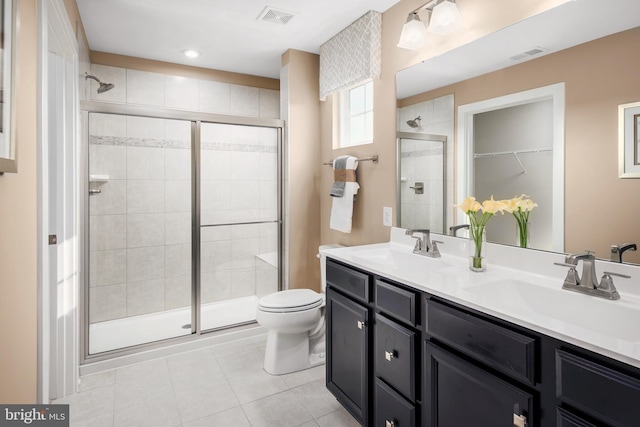 full bath with double vanity, a sink, visible vents, and a shower stall