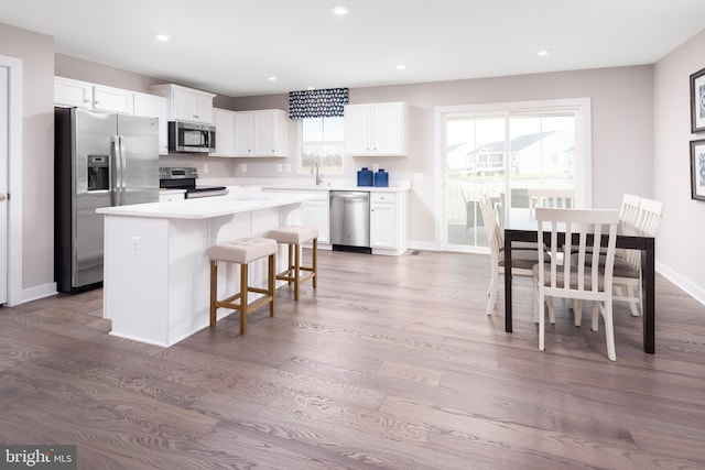 kitchen featuring white cabinets, a center island, stainless steel appliances, light countertops, and recessed lighting