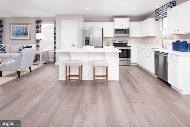 kitchen featuring a sink, stainless steel appliances, light countertops, and a center island