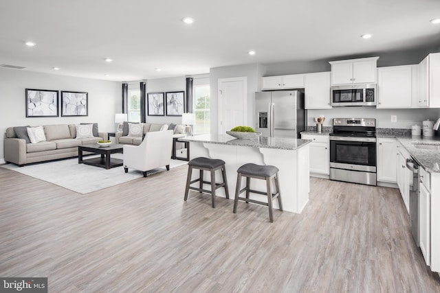 kitchen with a breakfast bar area, white cabinetry, open floor plan, appliances with stainless steel finishes, and a center island