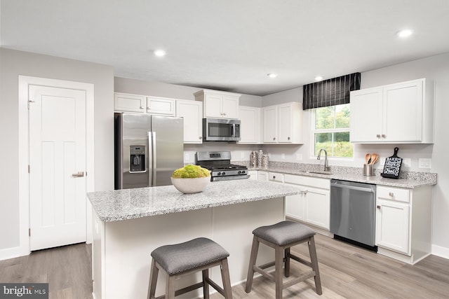 kitchen with a sink, stainless steel appliances, a kitchen island, and white cabinetry