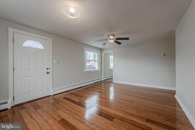 foyer entrance featuring baseboards, a textured ceiling, baseboard heating, and wood finished floors