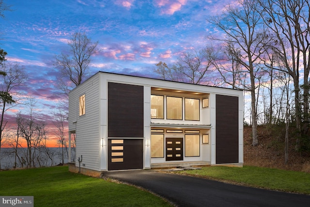 view of front of property featuring an attached garage, aphalt driveway, and a front yard