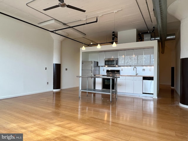 kitchen with appliances with stainless steel finishes, light wood-style floors, a sink, and ceiling fan