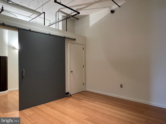 empty room with light wood-style floors, baseboards, and a barn door