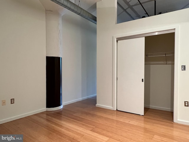 unfurnished bedroom with light wood-style flooring, baseboards, and a closet