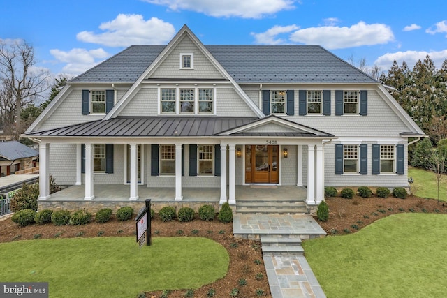 shingle-style home featuring metal roof, a porch, a standing seam roof, and a front yard