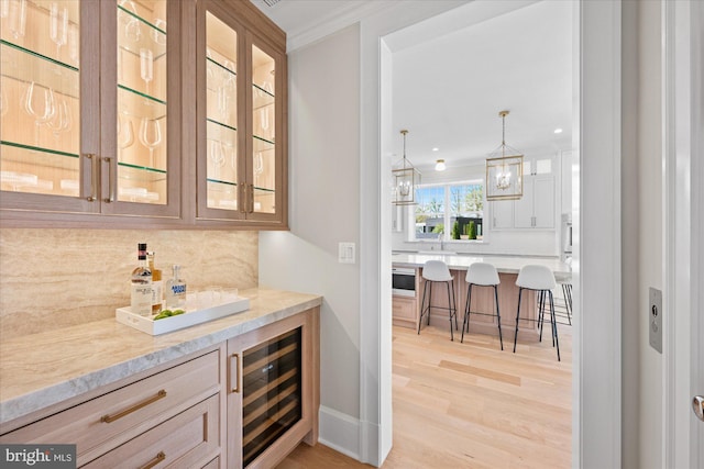 5408 Moorland Ln, Bethesda, MD 20814 - bar featuring wine cooler, decorative backsplash, ornamental molding, light wood-style floors, and decorative light fixtures