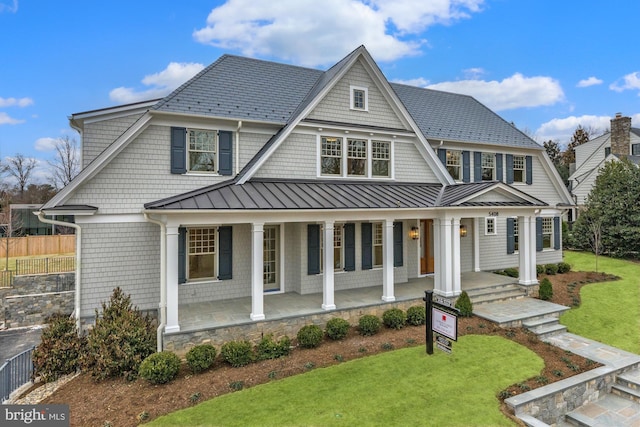 shingle-style home featuring a front yard, covered porch, metal roof, and a standing seam roof