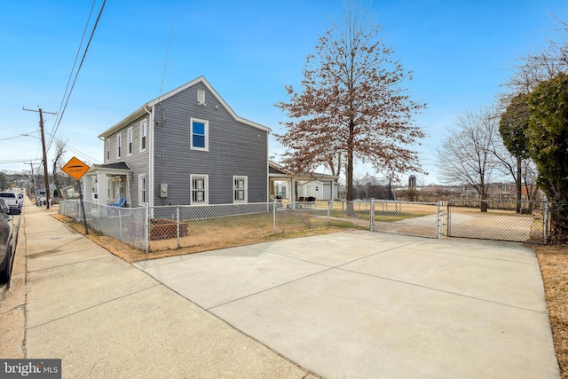 view of property exterior with a fenced front yard, a gate, and concrete driveway