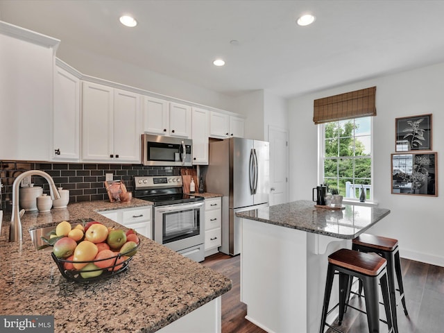 kitchen with sink, appliances with stainless steel finishes, white cabinets, and a center island