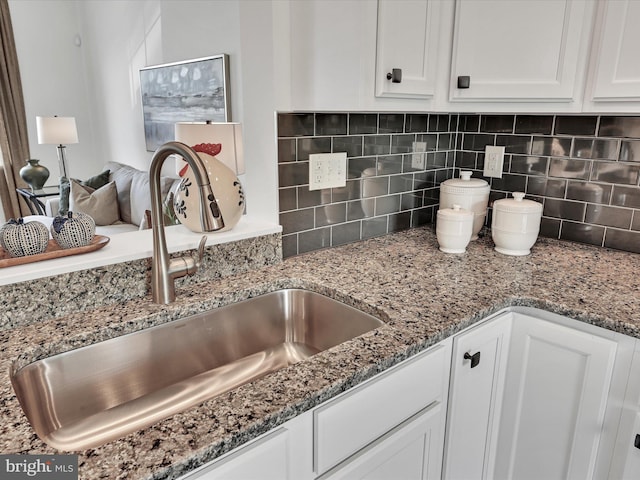 interior details featuring sink, white cabinets, and tasteful backsplash