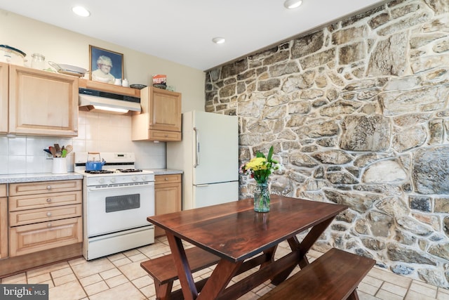 kitchen with white appliances, light countertops, under cabinet range hood, and light brown cabinetry