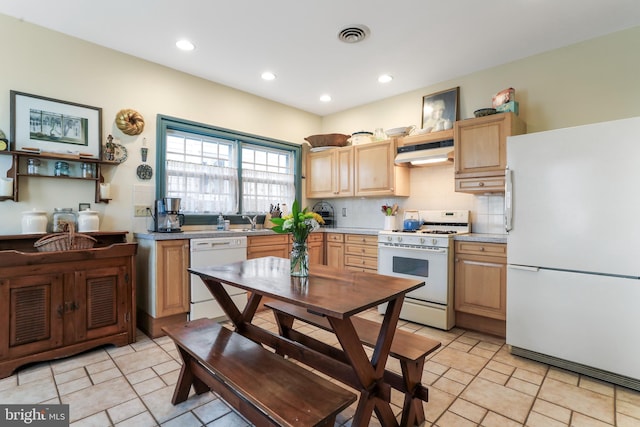 kitchen with tasteful backsplash, light brown cabinets, under cabinet range hood, light countertops, and white appliances