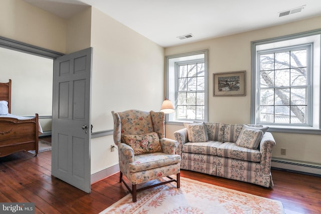 sitting room featuring visible vents, baseboard heating, baseboards, and hardwood / wood-style floors