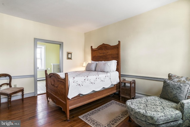 bedroom featuring a baseboard heating unit, baseboards, and hardwood / wood-style floors