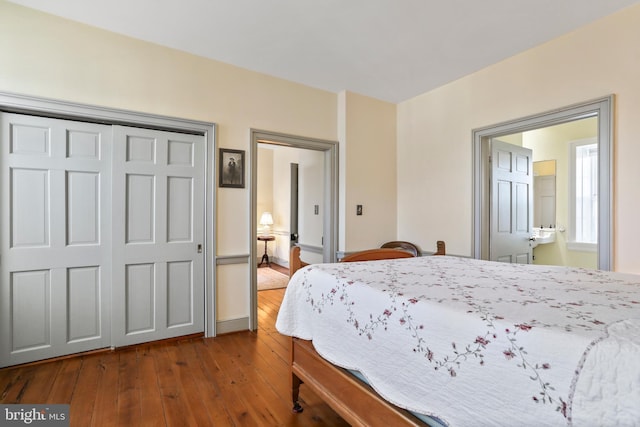 bedroom with a closet, ensuite bath, and dark wood-type flooring