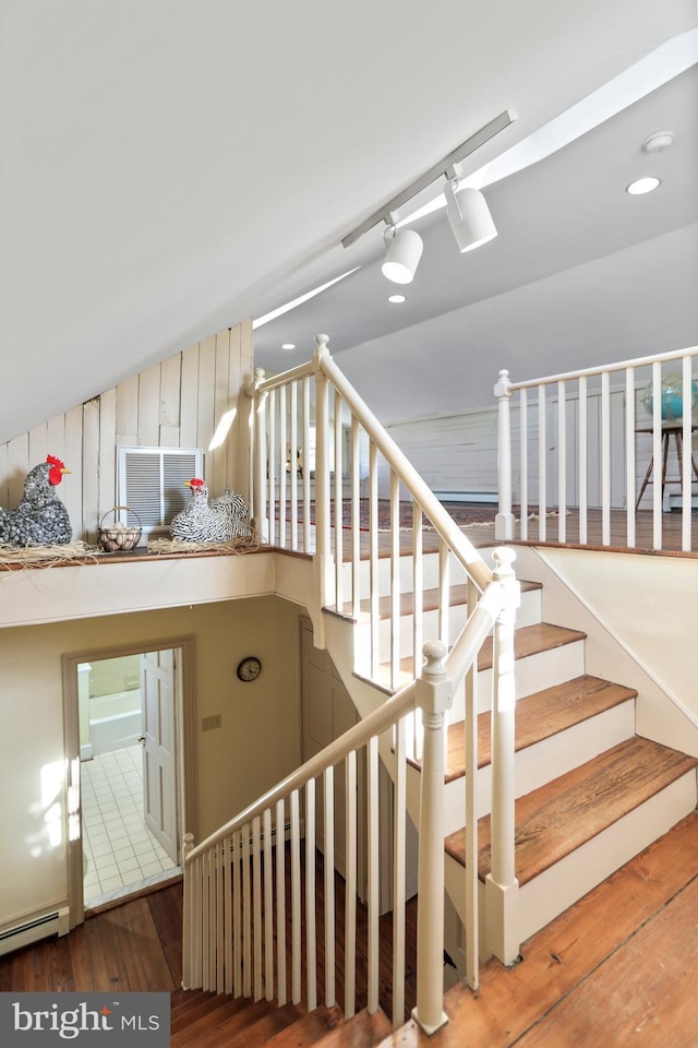 staircase featuring a baseboard heating unit and hardwood / wood-style floors